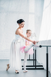 年轻老师摄影照片_可爱的孩子在粉红色的芭蕾舞短裙舒展, 而实践芭蕾与老师