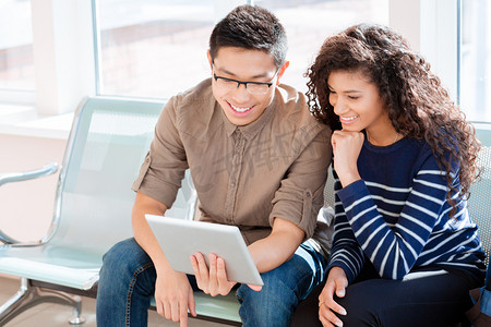 亚洲男孩和非洲裔美国女孩正在使用平板电脑