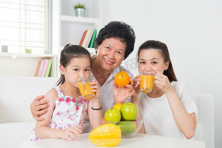 家庭时间摄影照片_亚洲家庭喝橙汁.