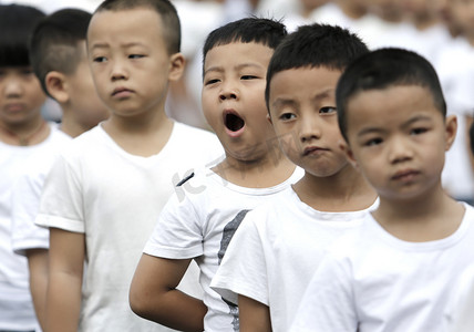 学校升旗仪式摄影照片_A young student yawns as he and other students attend a flag-raising ceremony of a new semester at a primary school in Guiyang city, southwest China's Guizhou province, 27 August 2018. 