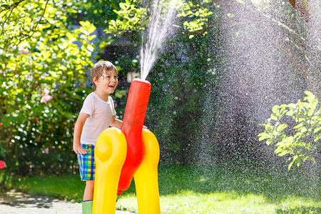 热男孩摄影照片_小小孩男孩玩一个花园软管和水