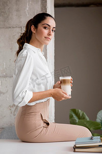 别致优雅摄影照片_侧面视图优雅的女商人摆姿势与咖啡