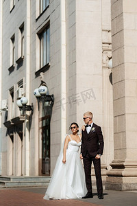在都市气氛中，身穿棕色西装的新郎和穿着白色裙子的新娘