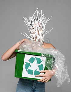 拿着回收站的女人脸上覆盖着白色塑料叉子