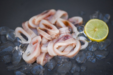 冰上鱿鱼圈，新鲜生鱿鱼配沙拉海鲜柠檬，黑色盘子背景