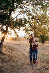 日落时分，一个拿着木板的快乐的男人和一个穿着格子衬衫散步的金发女孩