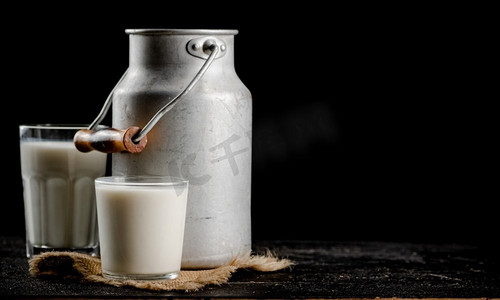 质朴的牛奶罐头和桌上的玻璃杯.工艺品容器