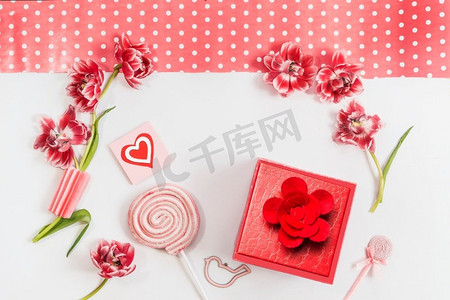 浪漫的情人节背景，心形，红色的鲜花，棒棒糖，礼品盒和白色背景的贺卡。俯视图。框架