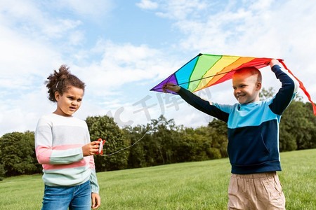 童年、休闲和人的概念-快乐的男孩和女孩在公园里放风筝。快乐的男孩和女孩在公园里放风筝