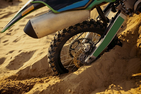 摩托车车轮被困在沙子里的特写。越野摩托比赛和速度越野赛。摩托车车轮被困在沙子里的特写