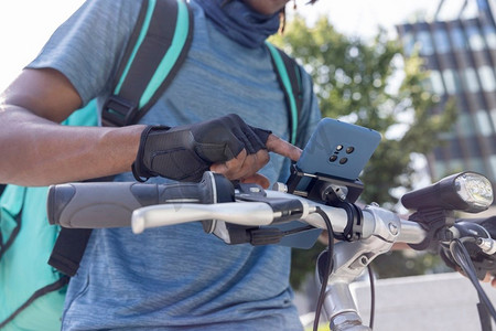 快递员骑自行车在城市里送外卖特写在手机上查看指示和订购细节