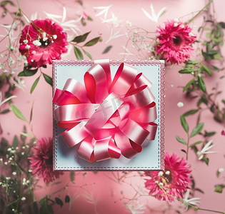 礼品盒，粉色丝带，花卉背景，粉色和白色的花朵。用美丽的礼物庆祝和问候。俯视图。