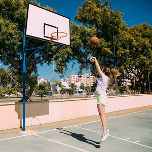 篮球场背景摄影照片_青少年女孩玩篮球场