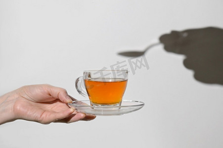 概念杯茶和勺子和手的影子