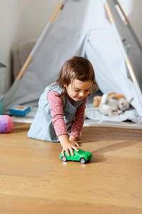 童年，hygge和人的概念—小女婴在家里玩玩具车。快乐的女婴玩玩具车在家里