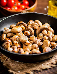 炸蘑菇摄影照片_在煎锅里自制的炸蘑菇。一个乡村背景。高质量的照片。在煎锅里自制的炸蘑菇。 
