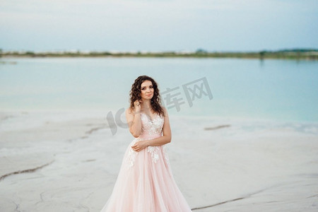 一个穿着粉红色裙子的女孩沿着沙漠的白色沙滩走着