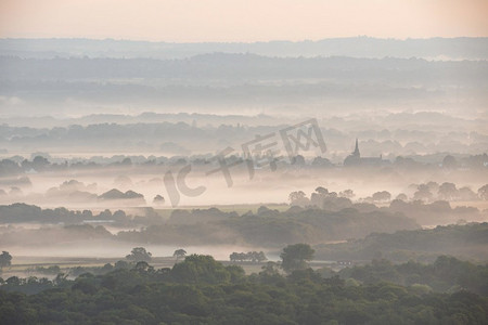 在雾蒙蒙的夏天日出时，层层薄雾翻滚在英国南部唐斯国家公园的乡村，令人惊叹。