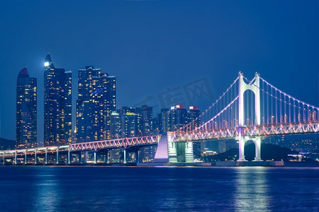 广安桥和摩天大楼在夜里被照亮。韩国釜山。夜晚的广安桥和摩天大楼。韩国釜山