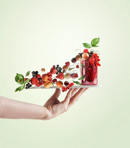 妇女手握托盘与红色果酱罐和各种飞行浆果和绿叶在淡绿色背景。创意食品悬浮概念
