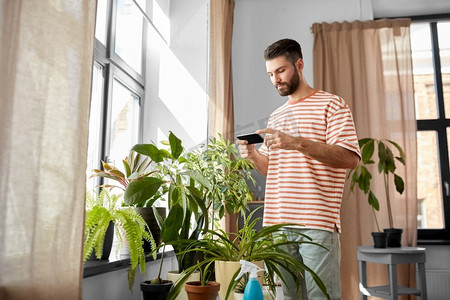 技术，人和互联网概念—人与智能手机和鲜花在家里。男子与智能手机和鲜花在家里