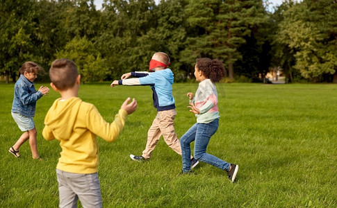 童年、休闲和人的概念-一群快乐的孩子在公园里玩捉迷藏游戏和跑步。快乐的孩子们在公园里玩耍和奔跑