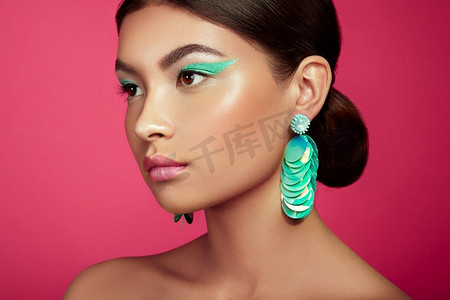 广告化妆摄影照片_美丽的韩国女人与大绿松石耳环。完美的化妆和优雅的发型。绿松石化妆箭头和粉红色唇膏