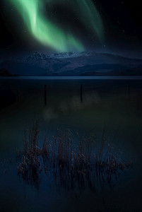 令人惊叹的充满活力的北极光在洛蒙德湖和山脉的景观在苏格兰极光合成图像
