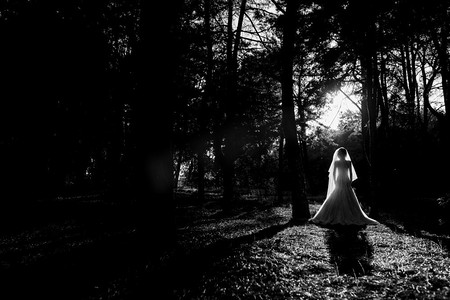 女孩在一个结婚礼服在秋天森林对野生树的背景