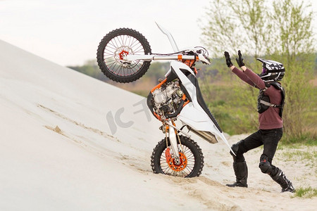 逐步提高摄影照片_时髦的男子提高摩托车沙漠