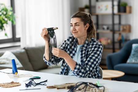 DIY，手工和爱好概念—妇女做或打结macrame在桌子上在家里。妇女做或打结在桌子上在家里