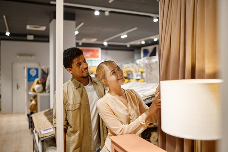 幸福的多种族家庭夫妇在家具店选择纺织窗帘购物。选择窗帘购物的幸福夫妻