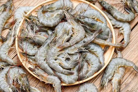生虾放在木盘和木板背景上烹饪，关闭新鲜的虾或对虾，海鲜搁鱼