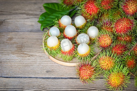 红毛丹果实收获从花园红毛丹树，新鲜和成熟的红毛丹甜热带水果去皮红毛丹与叶在木板