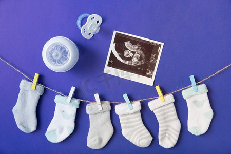 婴儿的袜子挂晾衣绳与奶瓶安抚奶嘴超声波图片蓝色背景