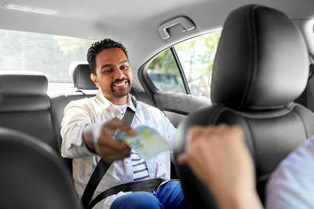 运输和支付概念—快乐的微笑印度男性乘客给钱出租车司机。快乐的男人给出租车司机钱