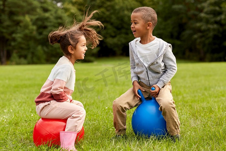 童年、休闲和人的概念快乐的孩子们在公园里跳跃着跳跃或弹跳球。在公园里快乐的孩子们在漏斗球上蹦蹦跳跳