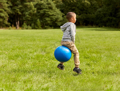 童年，休闲和人的概念—快乐的小男孩跳跃在跳球在公园。快乐的小男孩弹跳在hopper球在公园