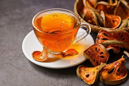 在玻璃上的贝尔茶与干燥的贝尔片在黑暗背景，贝尔汁—干贝尔水果茶健康—Aegle marmelos  