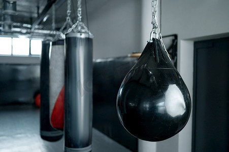 天花板上挂着不同的出气包，健身房里有拳击手训练和锻炼的运动器材。天花板上挂着不同的出气包