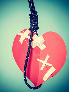 系在绳子上的红色心形小纸片。自杀，分手，糟糕的关系，有毒的恋情，心脏病学的概念..自杀绳索上的心脏