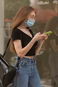 一名女子戴着医用口罩检查手机