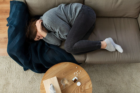 家里郁闷女摄影照片_心理健康、心理问题和抑郁症概念—强调妇女躺在家里沙发上。抑郁的女人躺在沙发上在家里