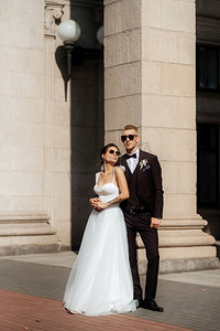 中马车摄影照片_穿着棕色西装的新郎和穿着白色连衣裙的新娘在城市的氛围中