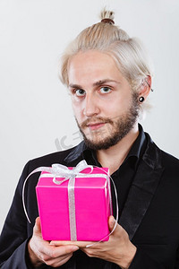 人们庆祝圣诞节，爱和幸福的概念-酷炫的年轻人手里拿着粉色的礼盒。一名男子手持粉色礼盒
