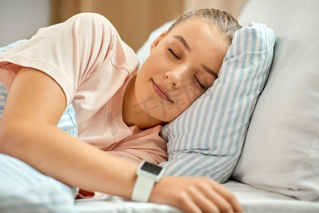 人，就寝时间和休息概念—女孩与智能手表睡在床上在家里。女孩与智能手表睡在床上在家里