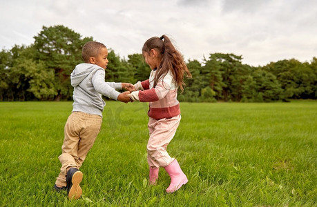 童年、休闲和人的概念-快乐微笑的小男孩和女孩在公园里玩耍。快乐的小男孩和小女孩在公园里玩得开心