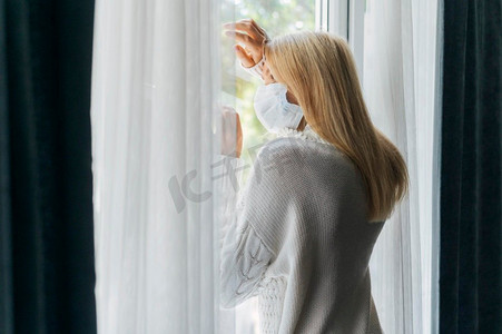 回家2019摄影照片_大流行病期间带着医用口罩回家的背影通过窗户看