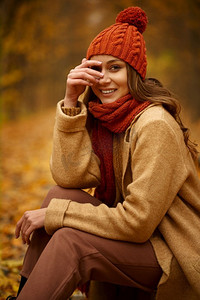 天象摄影照片_妇女美丽的秋天象象在森林或公园与橙色秋天叶子在模糊的背景。美丽的秋天肖像的妇女在森林