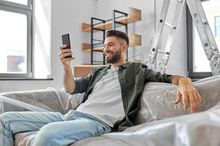 移动，人和房地产概念—快乐的微笑男子与智能手机在新家。带着智能手机的微笑男子搬进新家